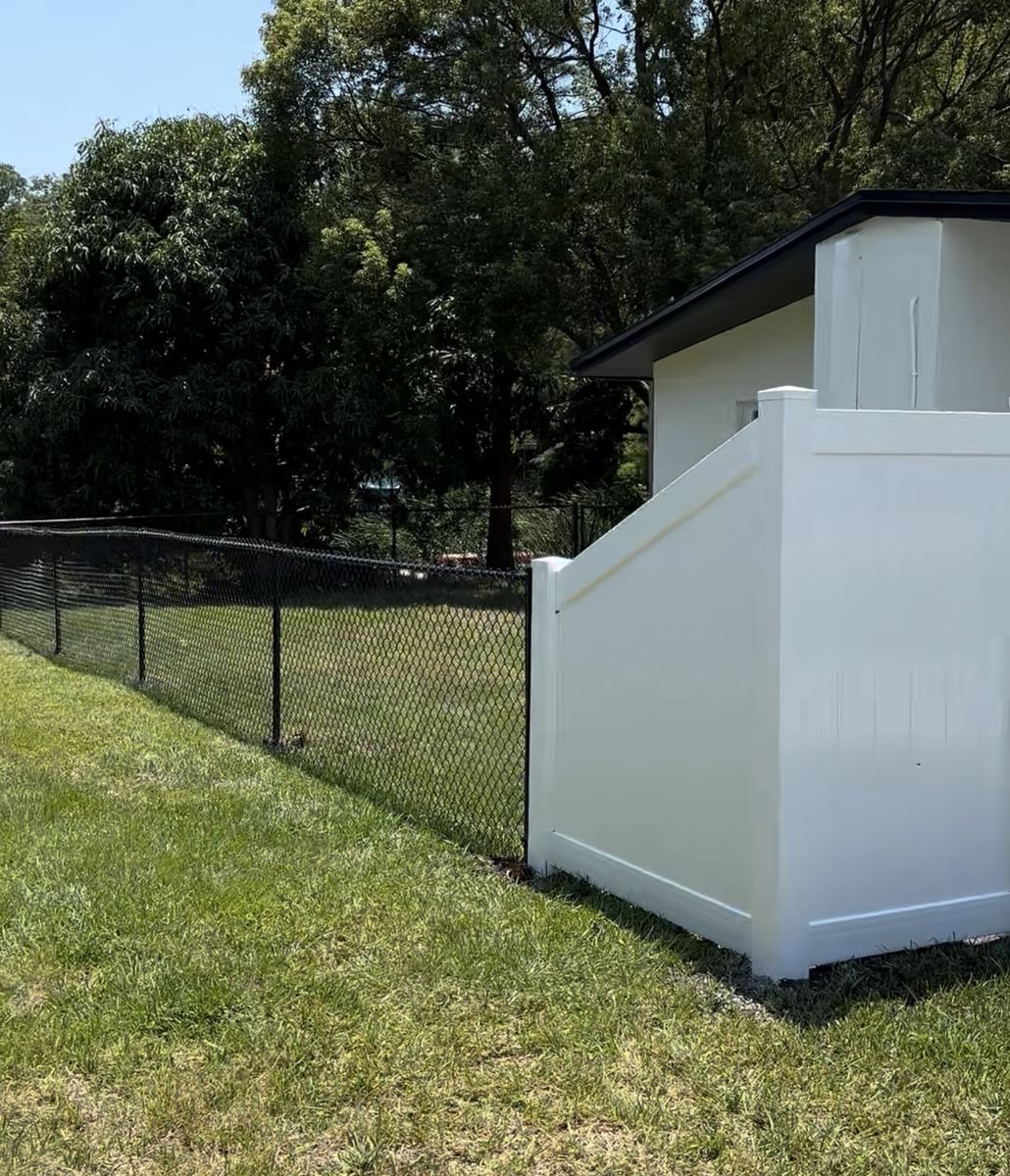 Black chain link fence transitioning into a white vinyl privacy fence at the side of a house, Florida