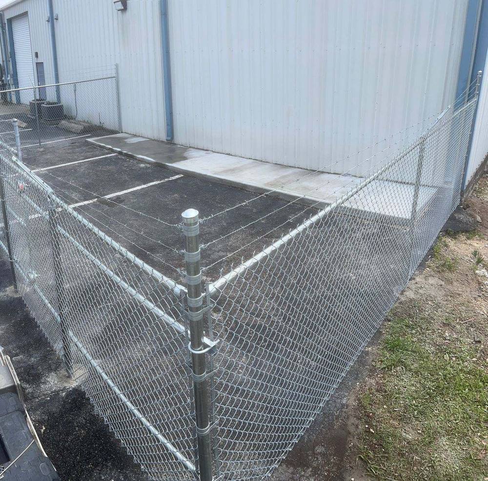 Commercial galvanized chain link fence with barbed wire top around a business parking area, Florida