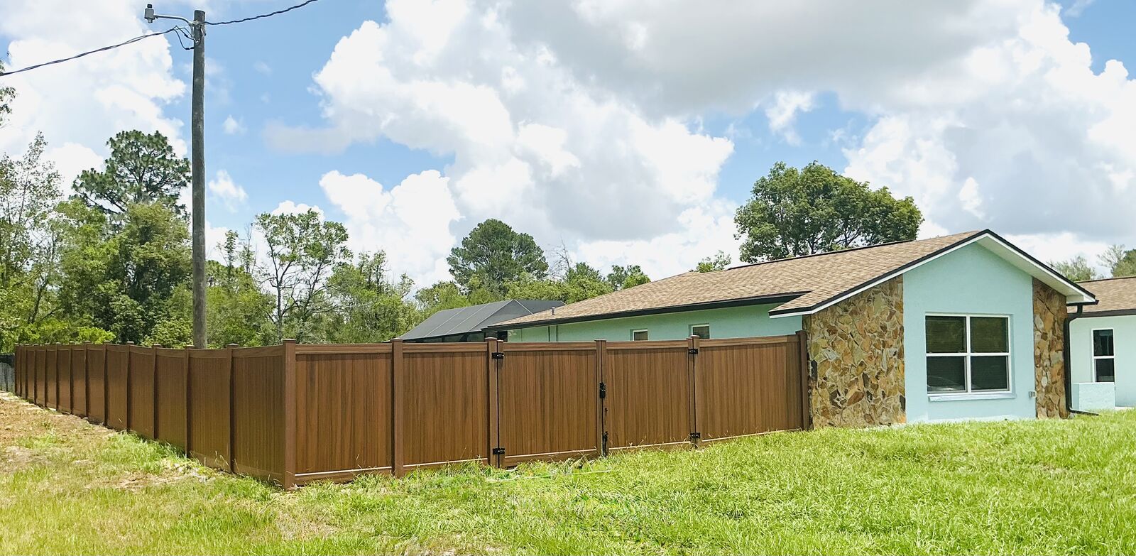 Long run of mocha walnut vinyl privacy fence with double gates in Spring Hill FL