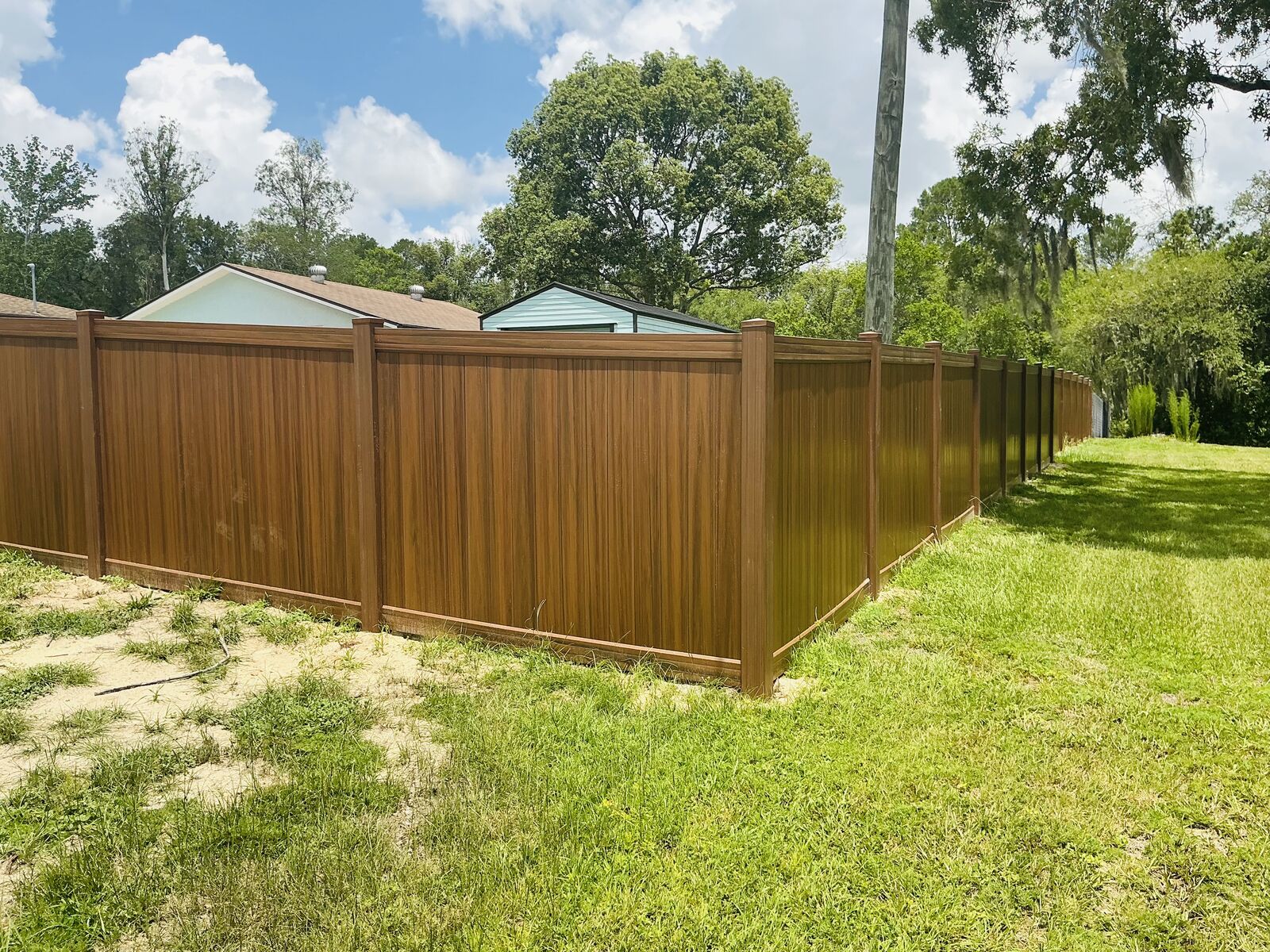 Mocha walnut wood-grain vinyl privacy fence installed in Spring Hill, FL