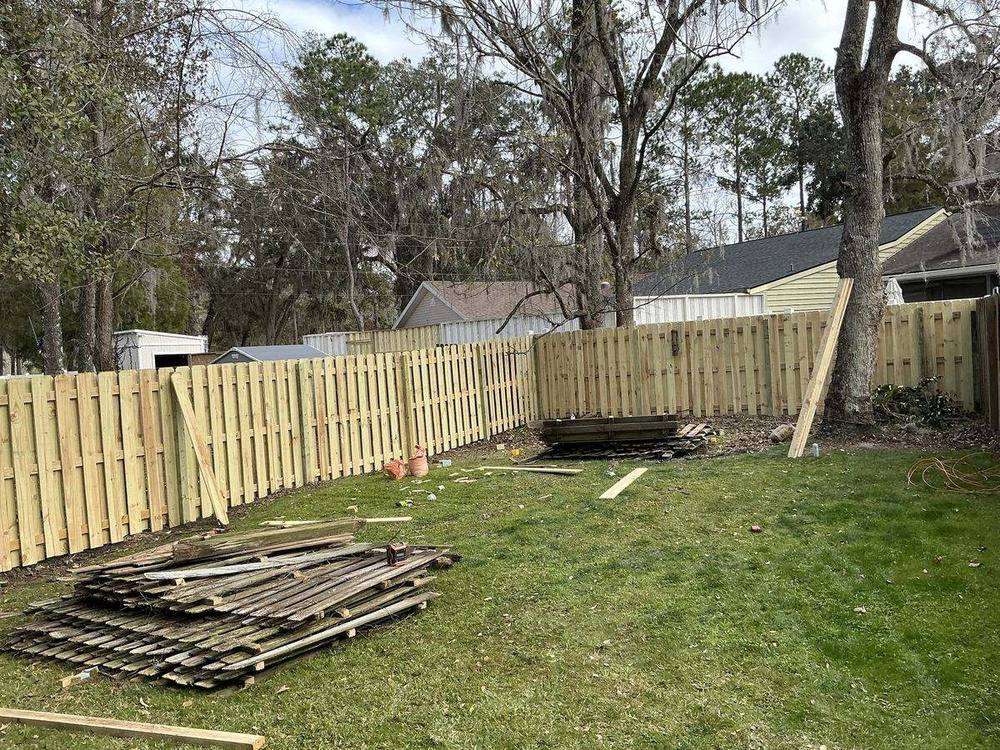 New shadow box wood privacy fence replacing an old weathered wood fence, old pickets stacked for removal, Florida