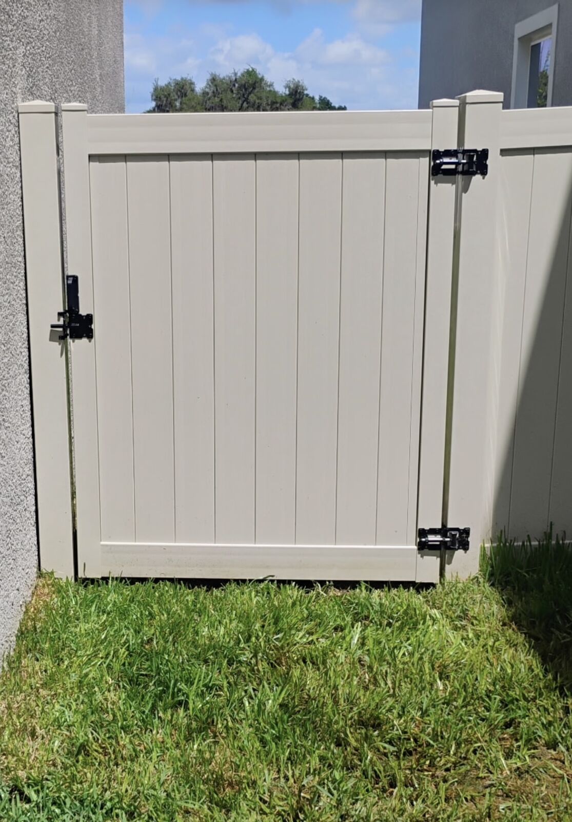 Tan vinyl fence walk gate with black hardware installed in Florida