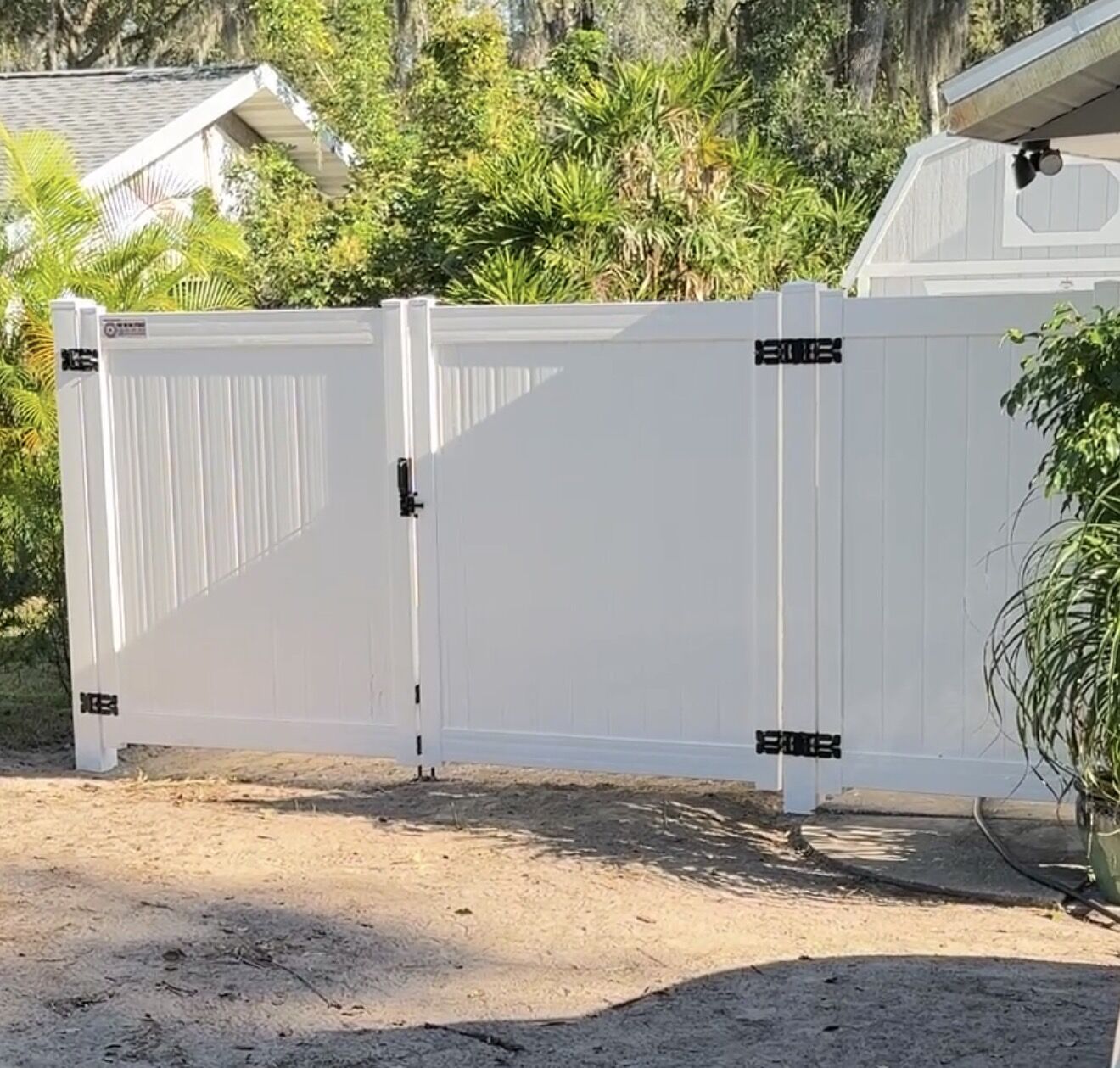 White vinyl privacy fence double drive gate with black hardware in Florida