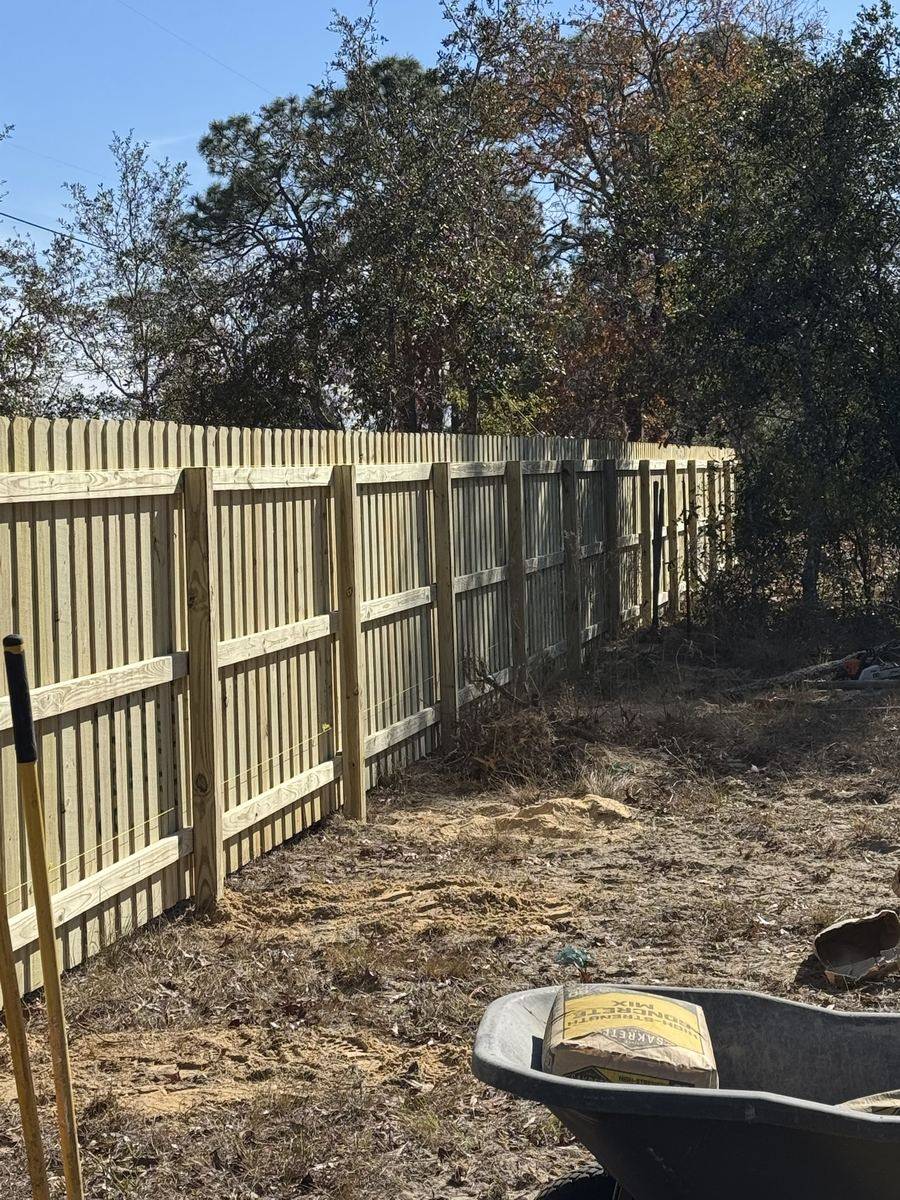 Long run of new pressure-treated pine dog-ear privacy fence, rail side with three rails, installed by Florida Friendly Fencing