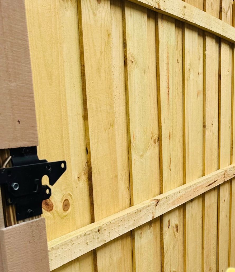 Wood privacy fence walk gate with black gravity latch hardware, side yard installation in Florida