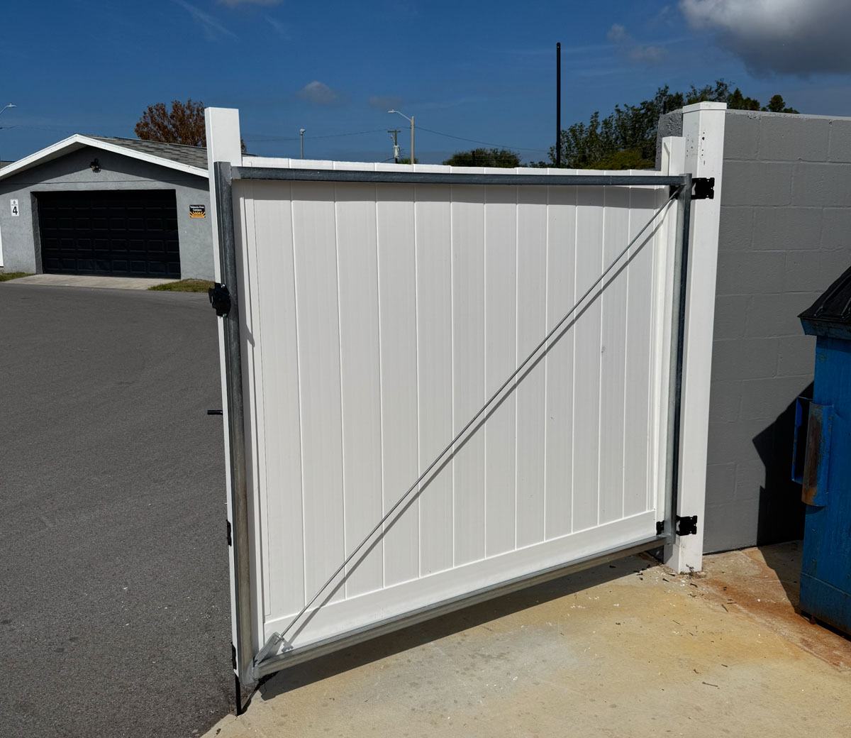Front view of a white vinyl dumpster enclosure in Brooksville, FL