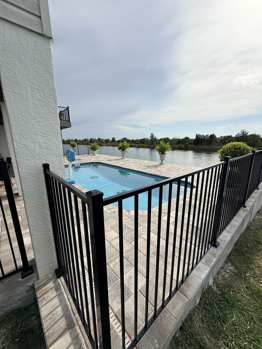 Black aluminum pool fence corner beside the pool in Hernando Beach, FL