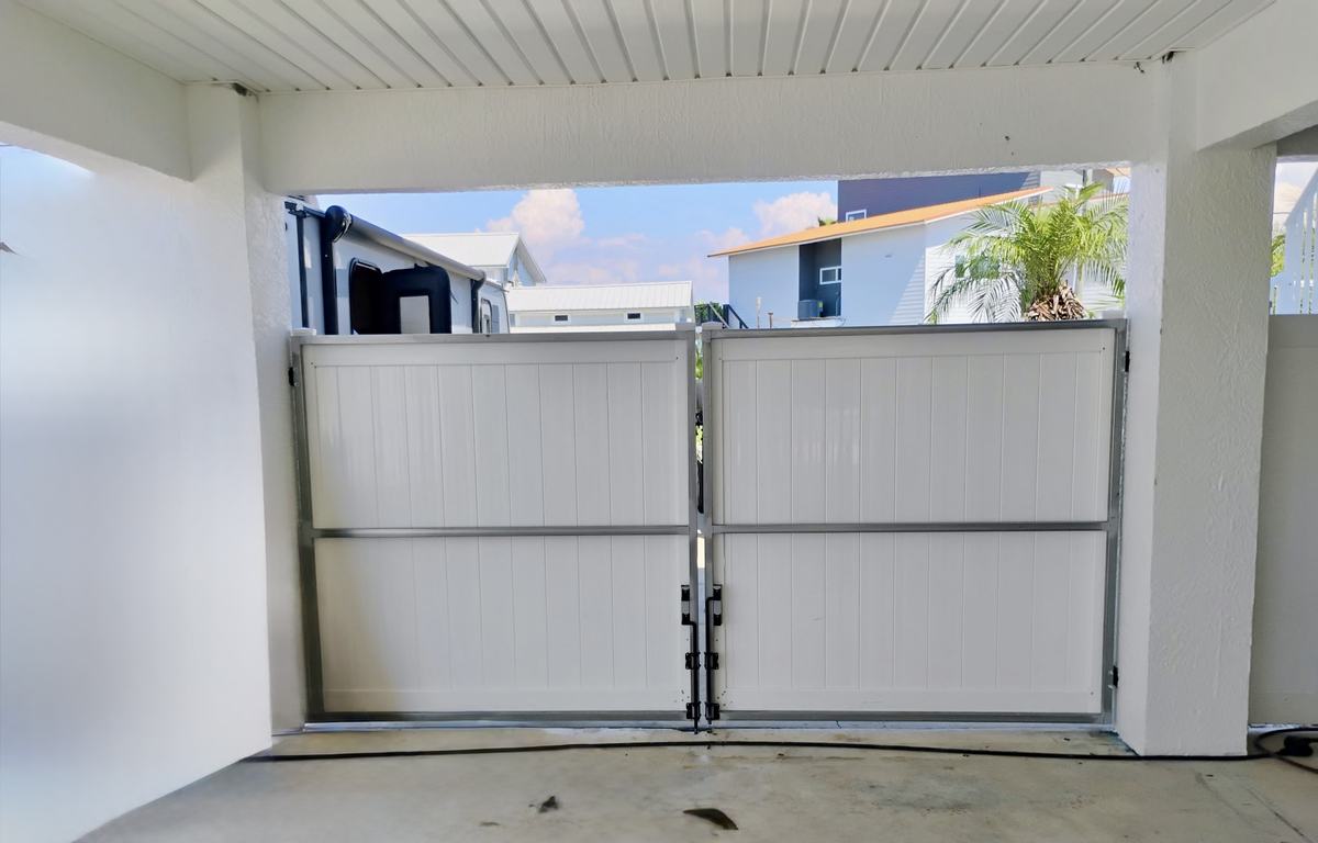 Steel-frame white vinyl double gates under a carport in Hernando Beach, FL