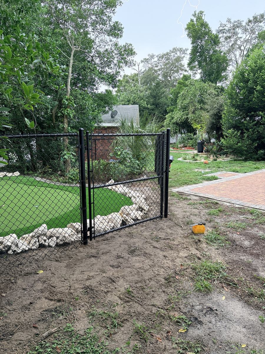 Black chain link gate beside a paver patio in Spring Hill, FL