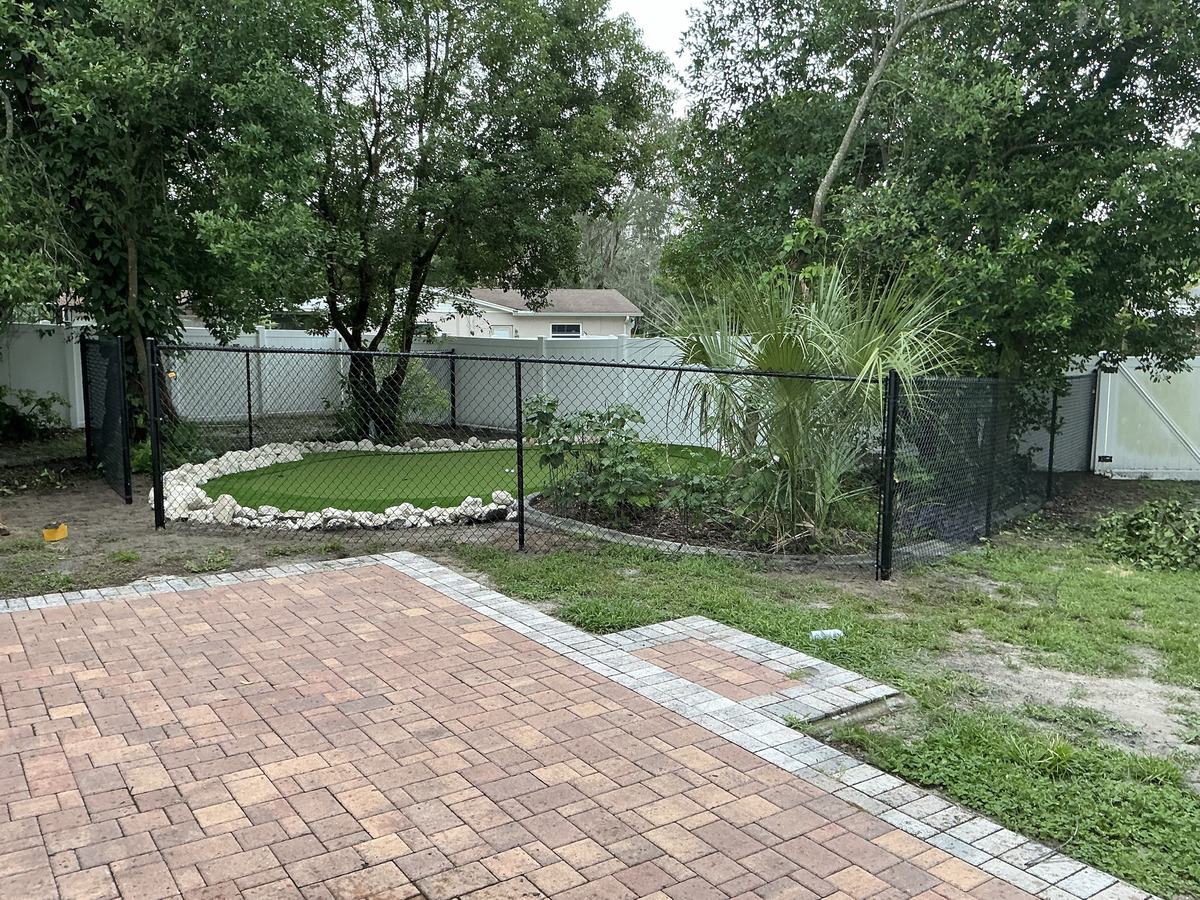 Black chain link fence around a backyard putting green in Spring Hill, FL