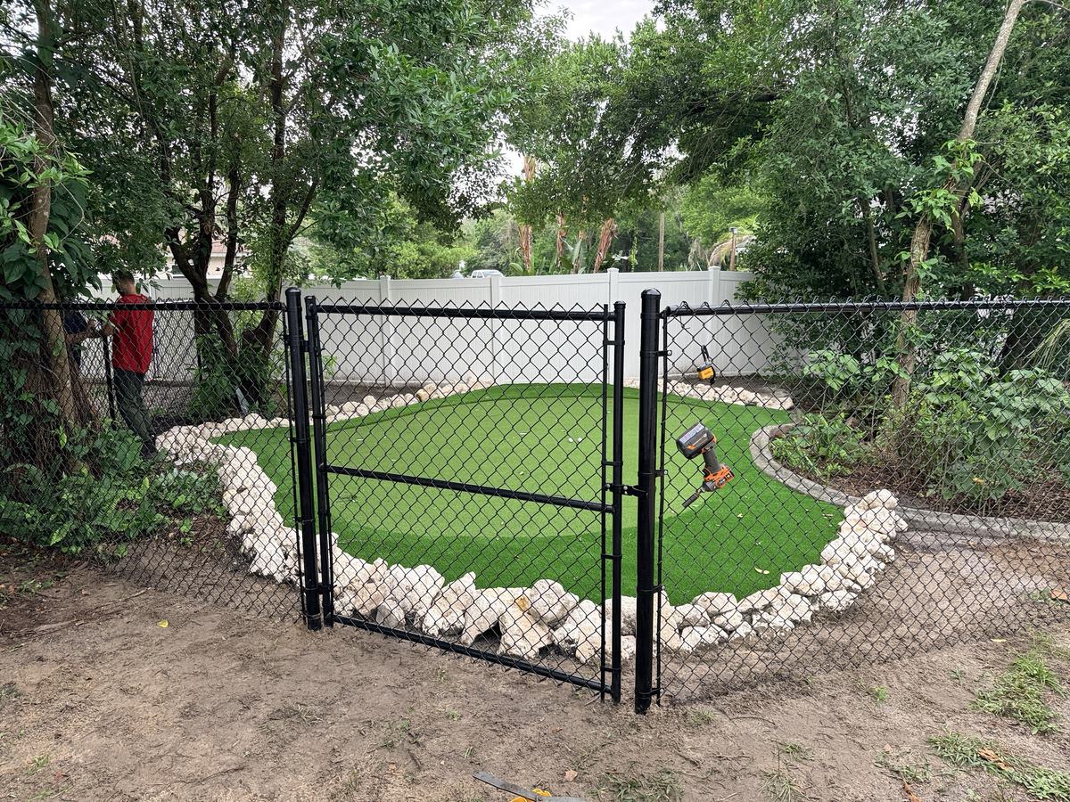Black chain link walk gate into a putting green in Spring Hill, FL