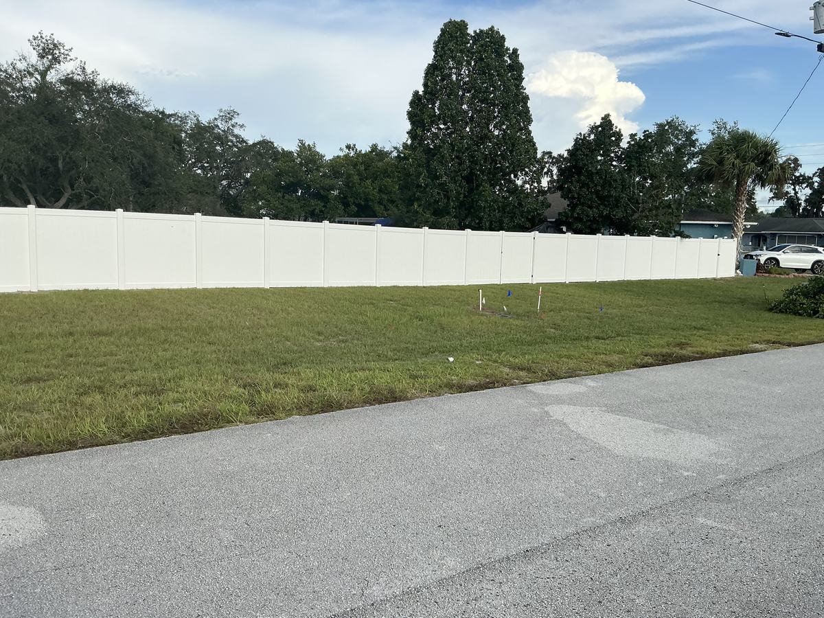 Street view of a long white vinyl privacy fence on a Spring Hill corner lot