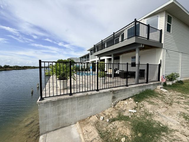 Black aluminum pool fence around a waterfront pool deck in Hernando Beach, FL