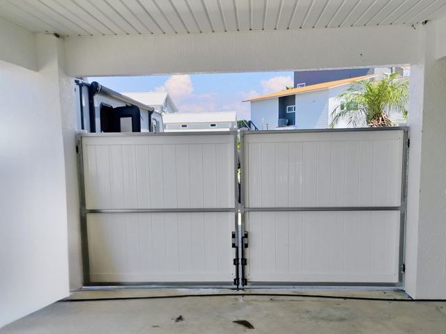 Steel-frame white vinyl double gates under a carport in Hernando Beach, FL