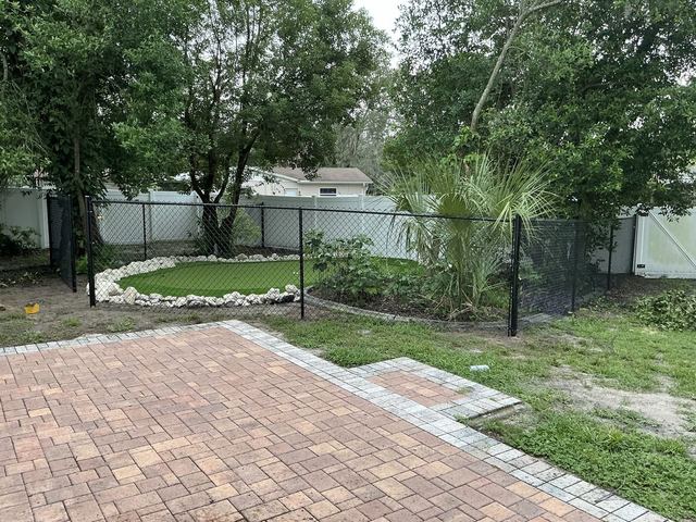 Black chain link fence around a backyard putting green in Spring Hill, FL