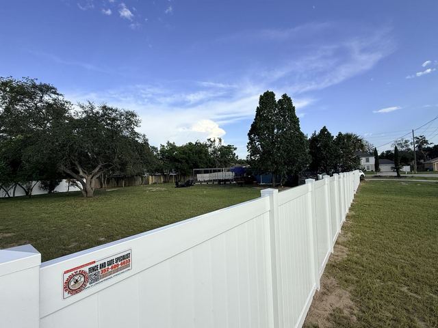 Long white vinyl privacy fence with a Florida Friendly Fencing sign in Spring Hill, FL