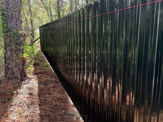 Black Dura Fence privacy fence along a tree line in Weeki Wachee, FL