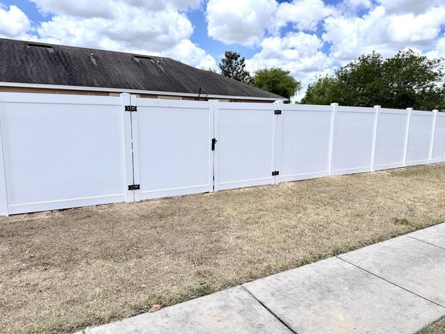 White vinyl privacy fence installation along a sidewalk